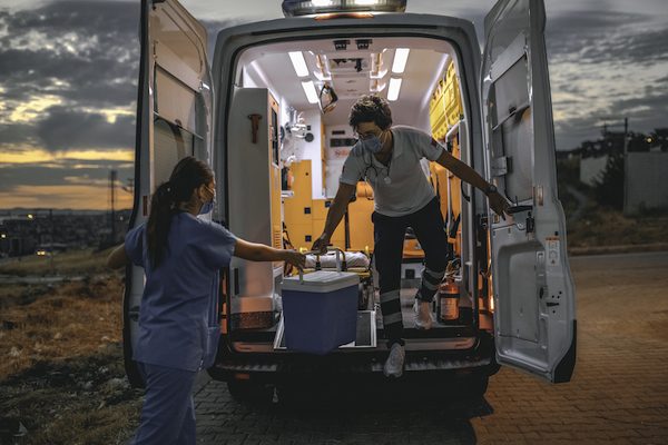 Medical team in a hurry carrying organ transplants box by ambulance during pandemic